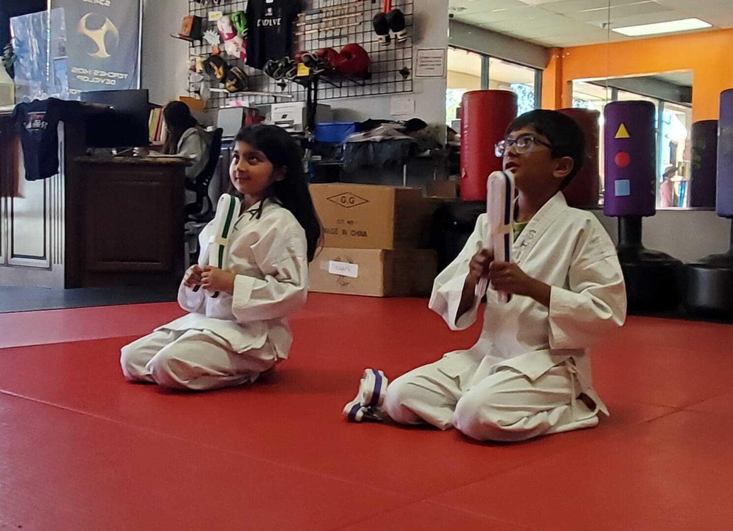 Two children in white outfits practicing martial arts.